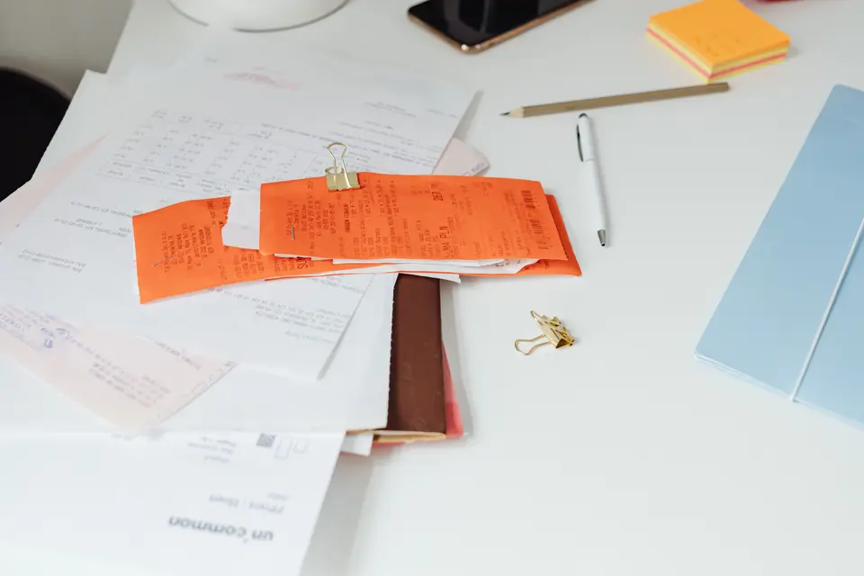 A stack of paper receipts and invoices waiting to be coded